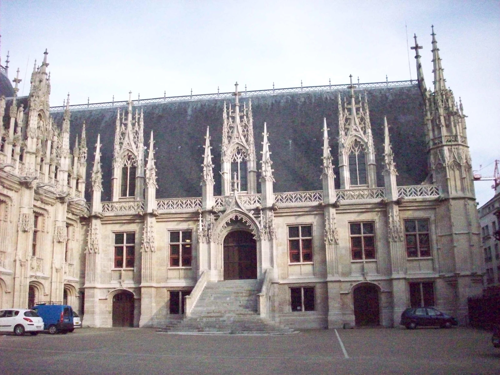 Façade gothique du palais de justice de Rouen, donnant sur une cour avec un escalier central.