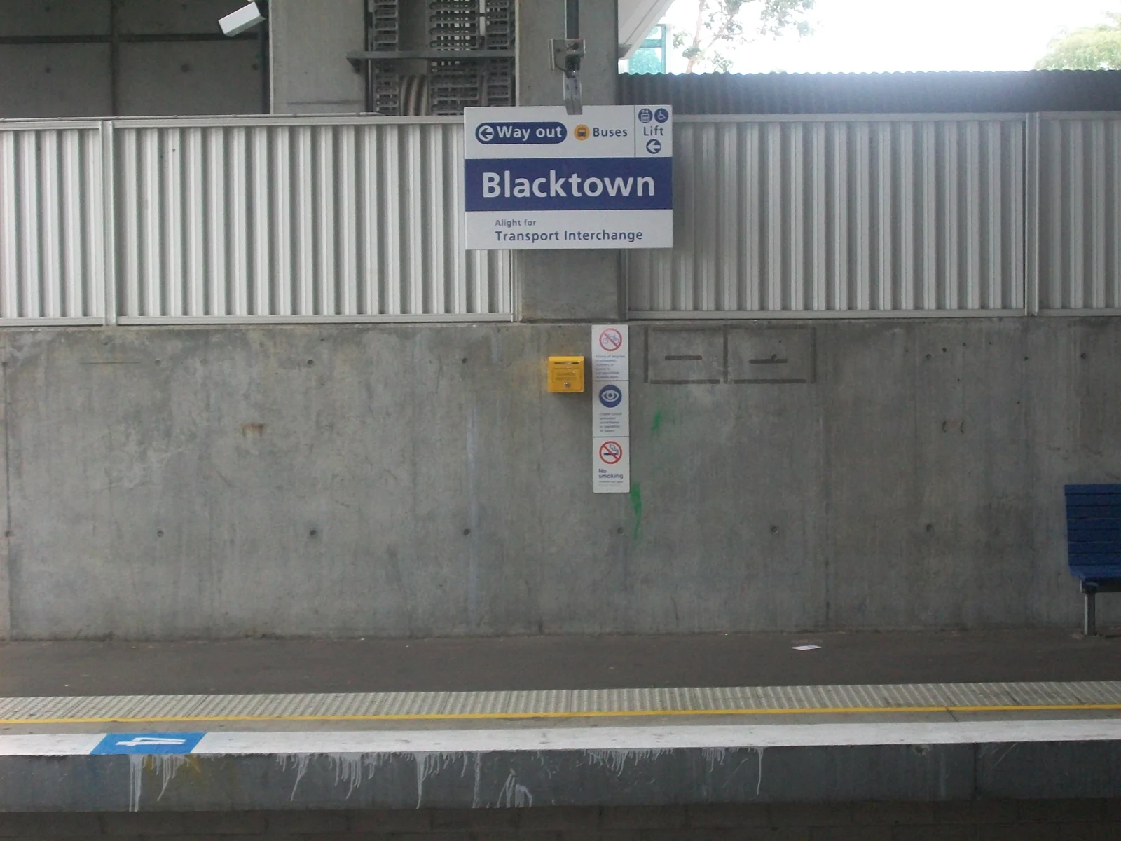 Panneau « Blacktown » au-dessus d’un quai vide, devant une paroi de béton et une clôture métallique.