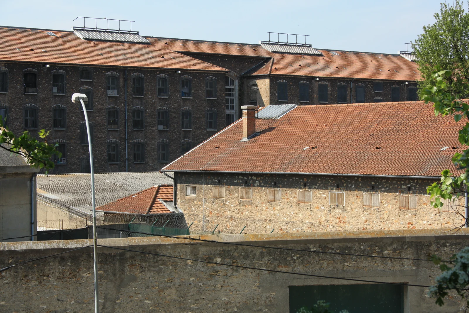 Bâtiments de pierre, fenêtres à barreaux et toitures de la prison de Fresnes, vus de l’extérieur.