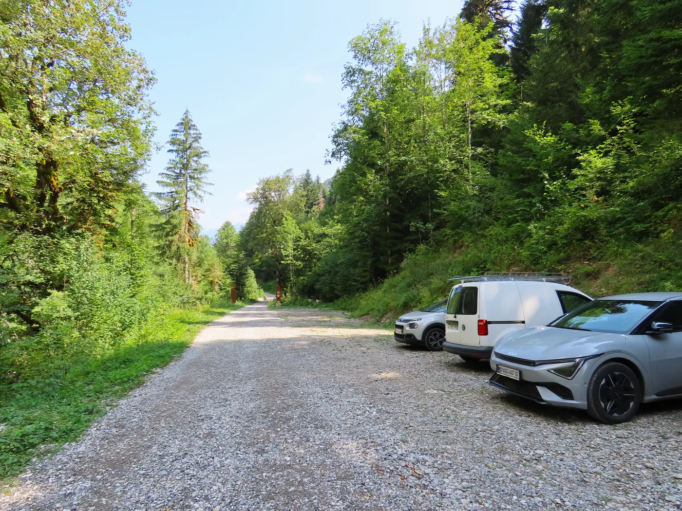 Parking du Martinet dans la combe d’Ire, entouré de forêt, avec des véhicules stationnés en 2026.