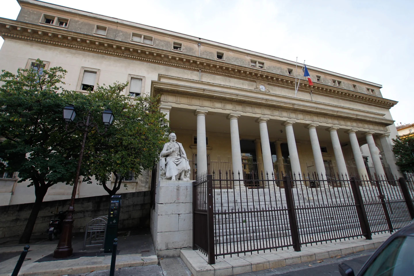 Façade à colonnes du palais de justice d’Aix-en-Provence, derrière une grille, avec la statue de Portalis.