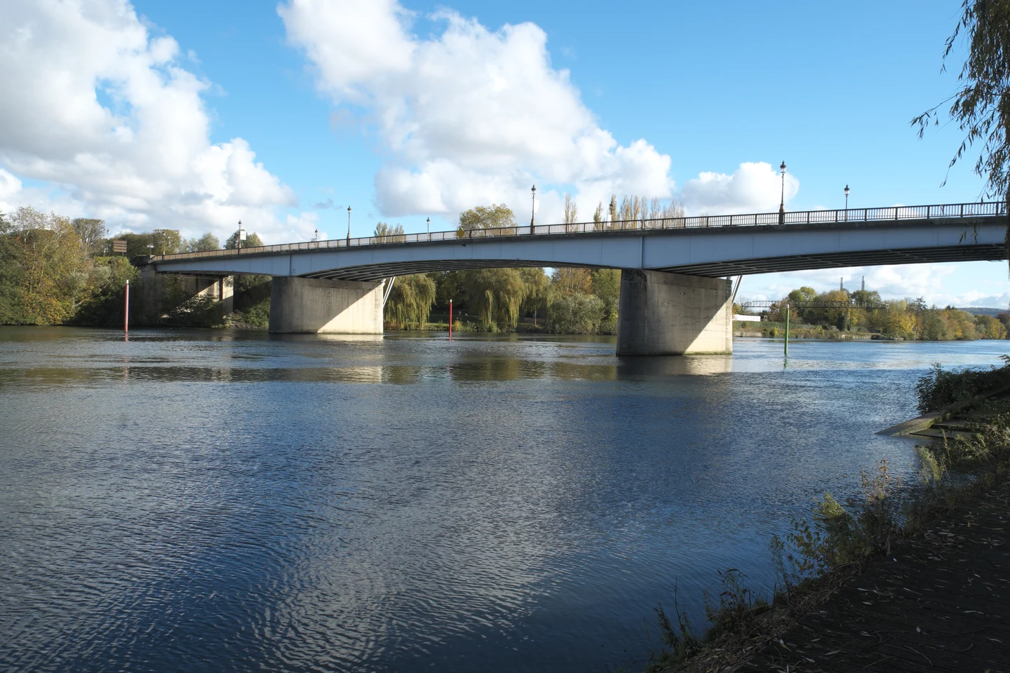 Le Pont Neuf franchissant la Seine à Mantes-la-Jolie, sous un ciel bleu et nuageux.