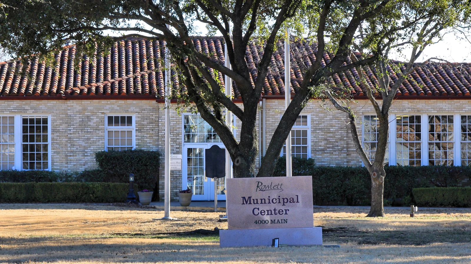Façade du centre municipal de Rowlett, au Texas, derrière des arbres et un panneau Municipal Center.