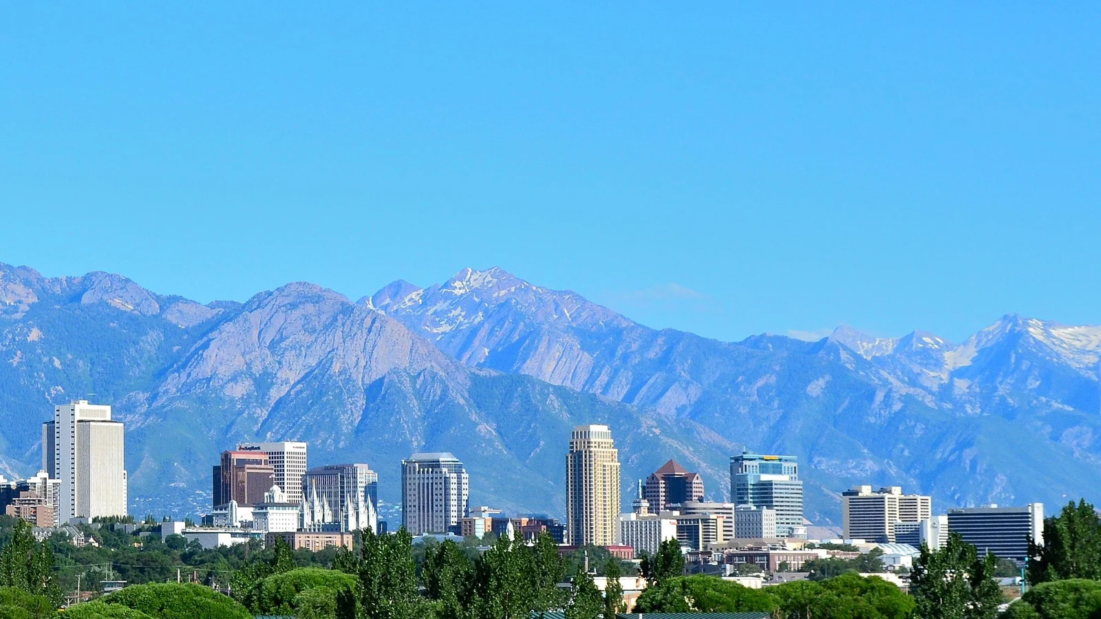 Vue du centre de Salt Lake City, avec ses immeubles devant les montagnes et un vaste ciel bleu.