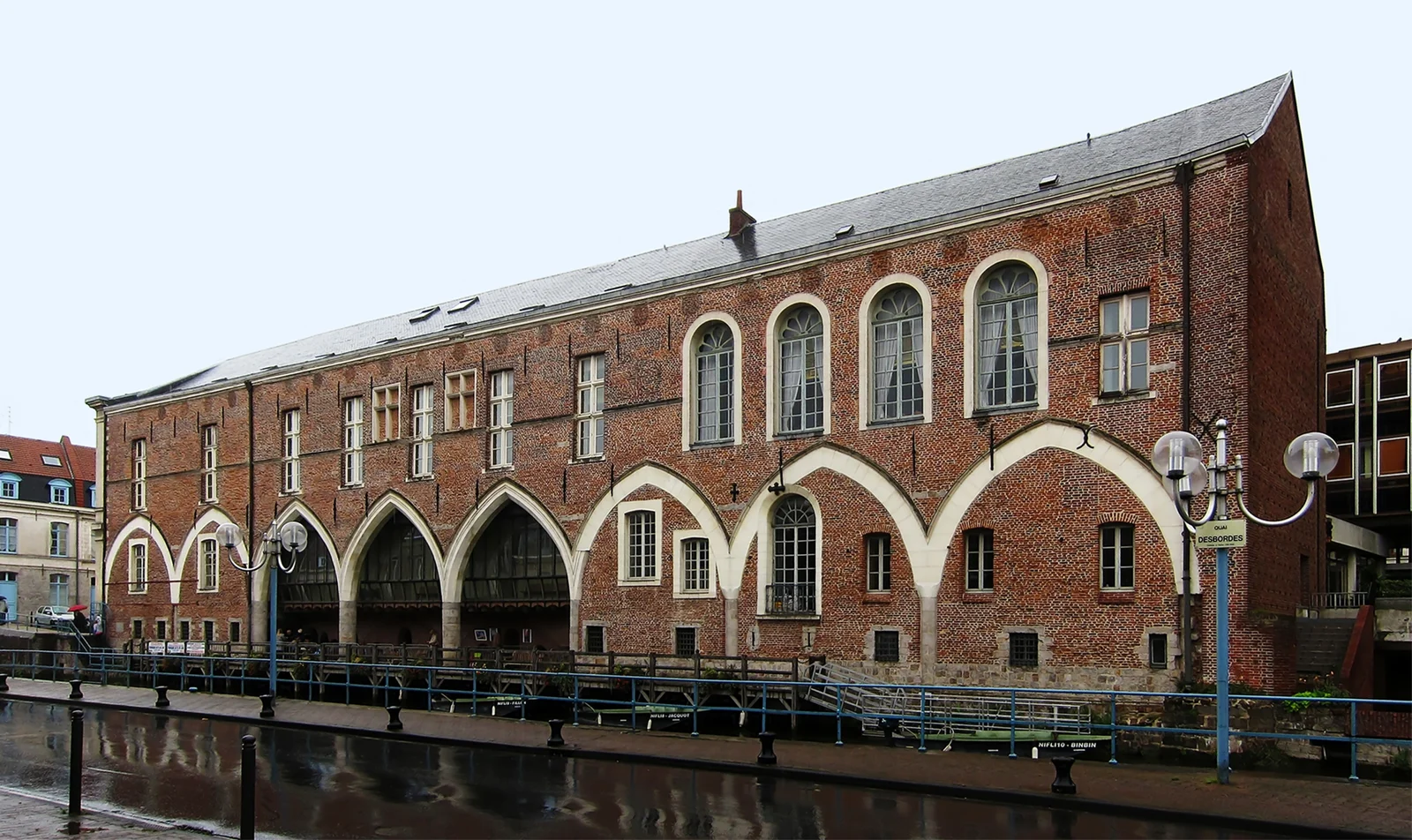 Longue façade en briques et grandes arcades du palais de justice de Douai, au bord de la Scarpe.
