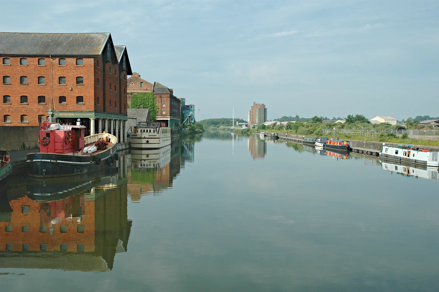 Le canal de Gloucester et Sharpness, bordé d’anciens entrepôts de brique et de bateaux amarrés, vu depuis Llanthony Road Bridge.