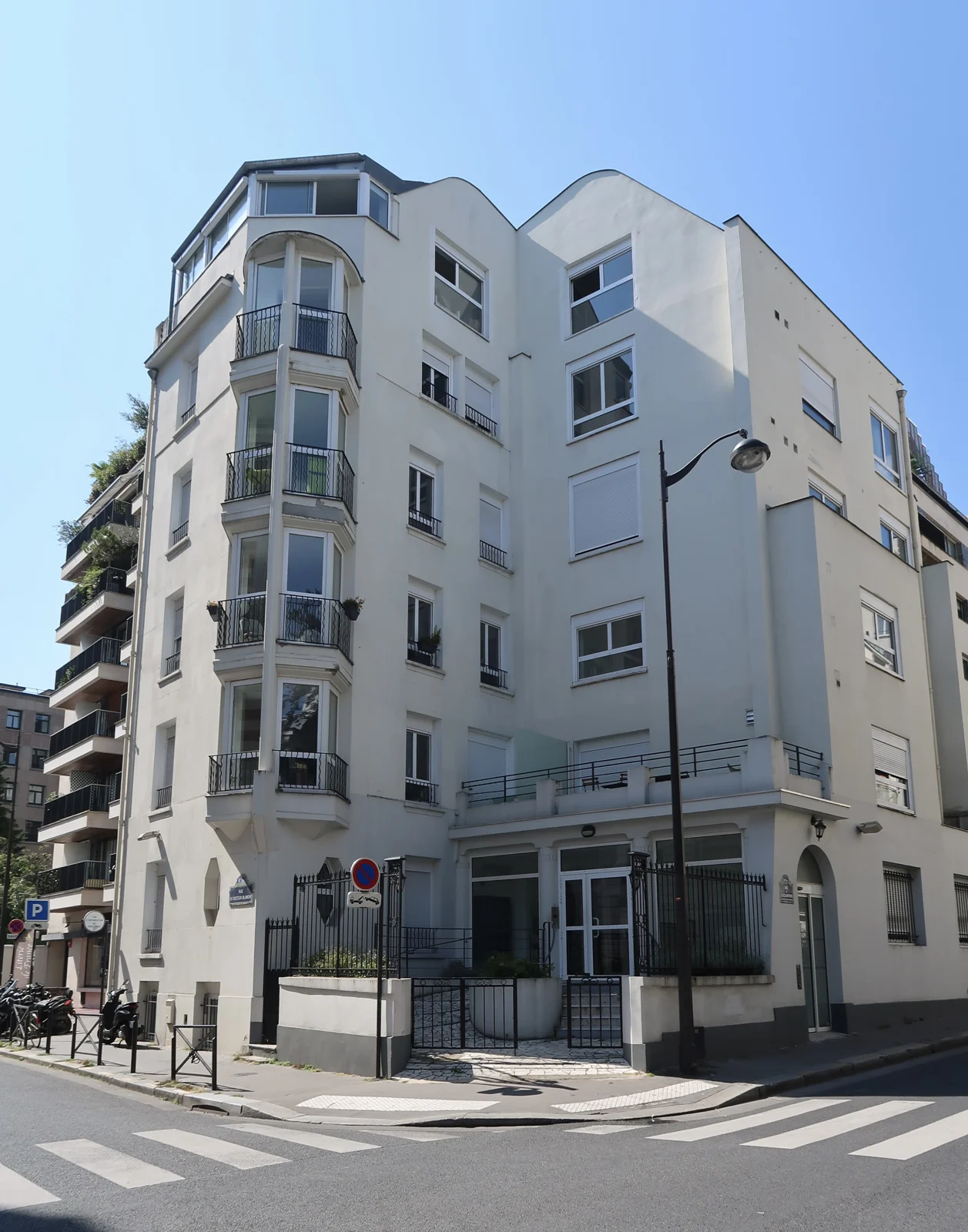 Immeuble clair à l’angle des rues du Docteur-Blanche et de l’Assomption à Paris, photographié depuis la chaussée.