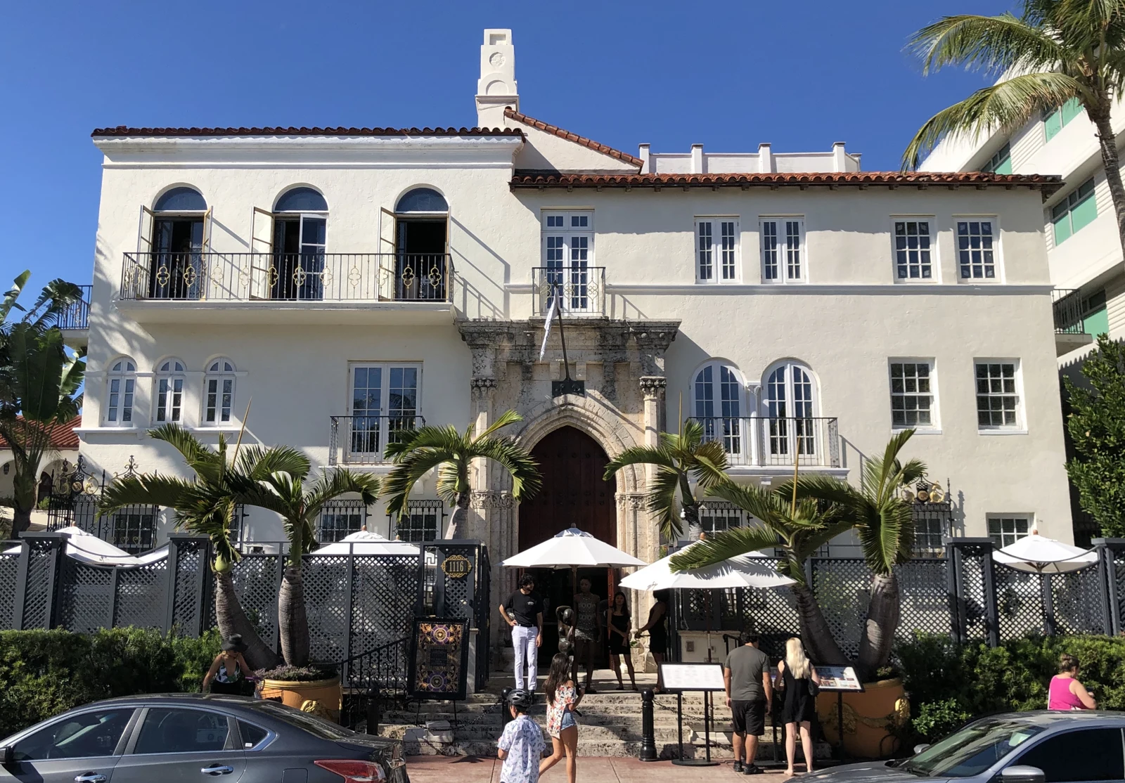 La façade blanche de Casa Casuarina, son portail central et ses palmiers, vus depuis Ocean Drive à Miami Beach.