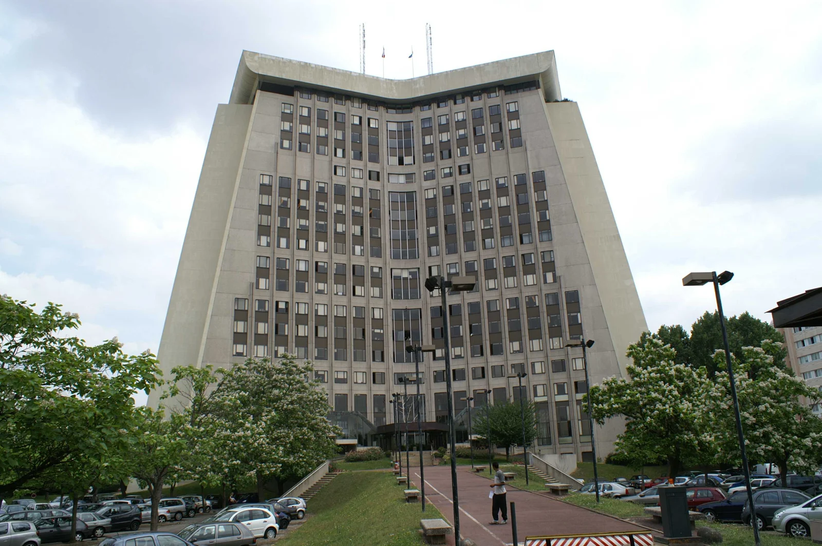 Le haut bâtiment de béton du palais de justice de Créteil, vu depuis son parvis planté d’arbres.