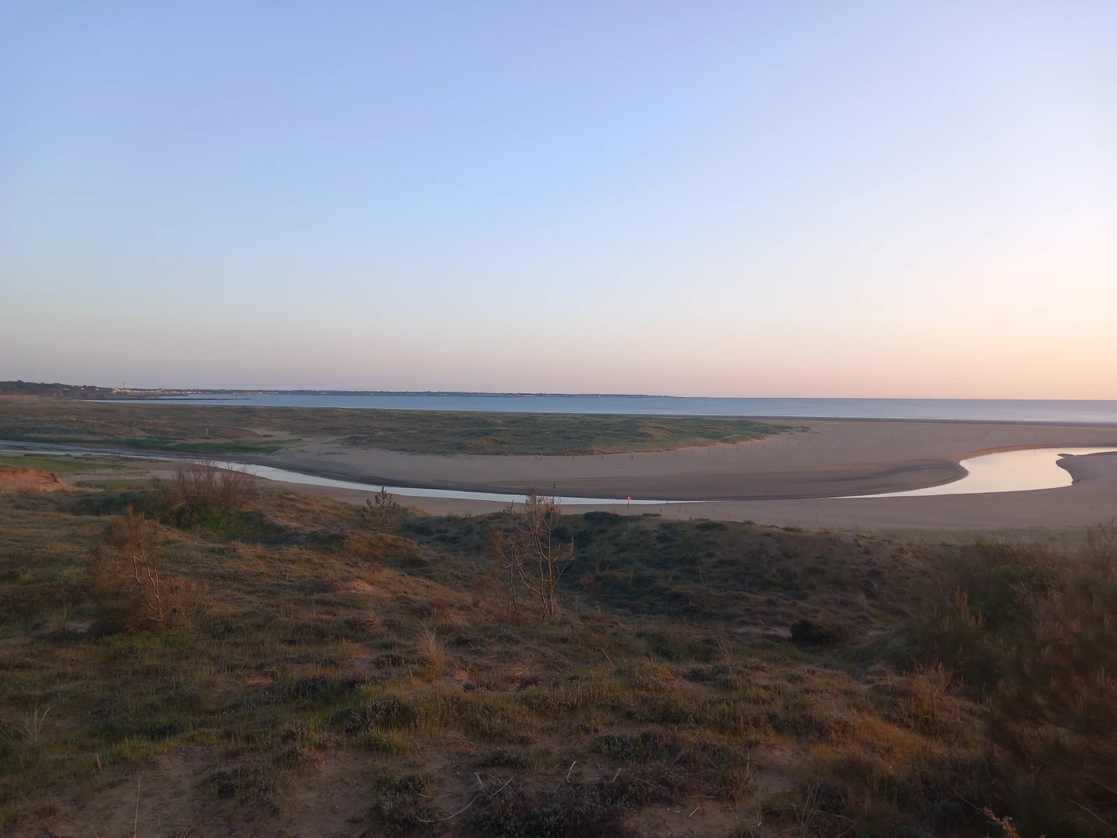 Le chenal du Boivre traverse la plage de Saint-Brevin-l’Océan entre les dunes et la mer au coucher du soleil.