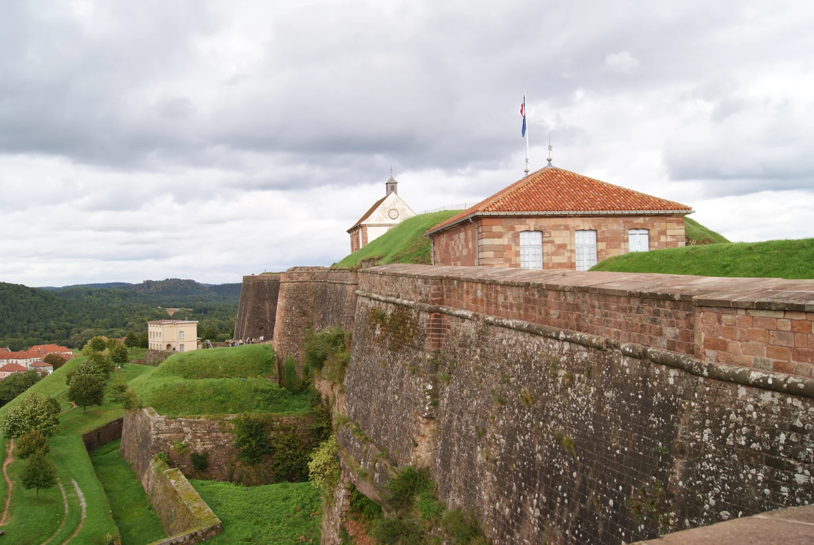 Les remparts de grès de la citadelle de Bitche, ses bâtiments et les collines à l’arrière-plan.