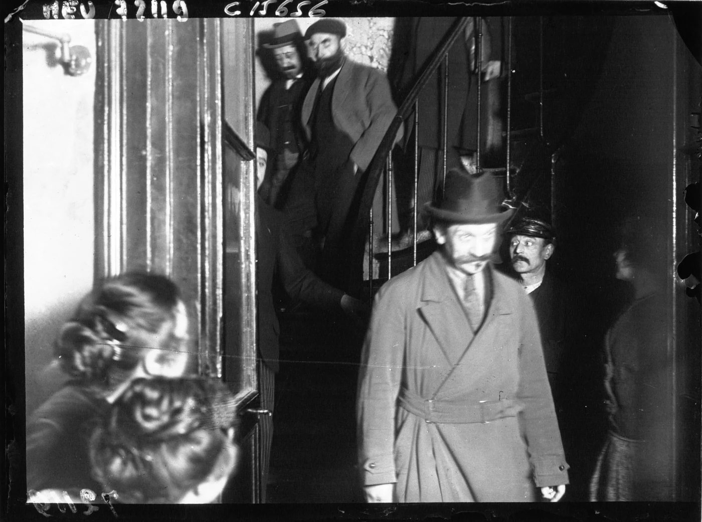 Henri Désiré Landru descendant les escaliers de son domicile parisien, entouré de plusieurs hommes, en mai 1919.