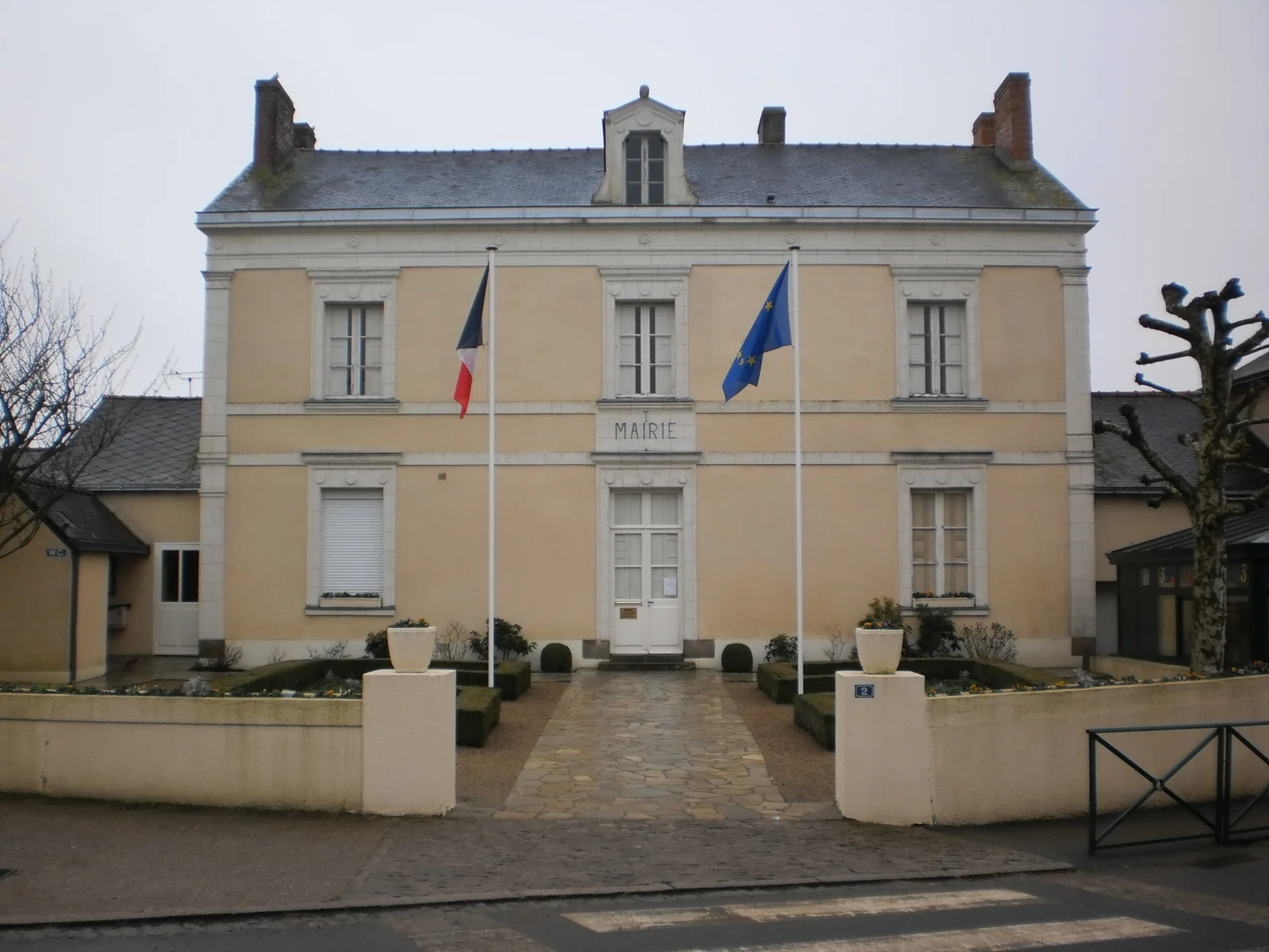 Façade claire de la mairie de La Chapelle-Saint-Sauveur, avec les drapeaux français et européen.
