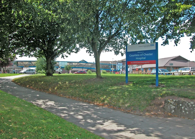 Panneau d’entrée du Countess of Chester Hospital devant les bâtiments de l’hôpital et des arbres.