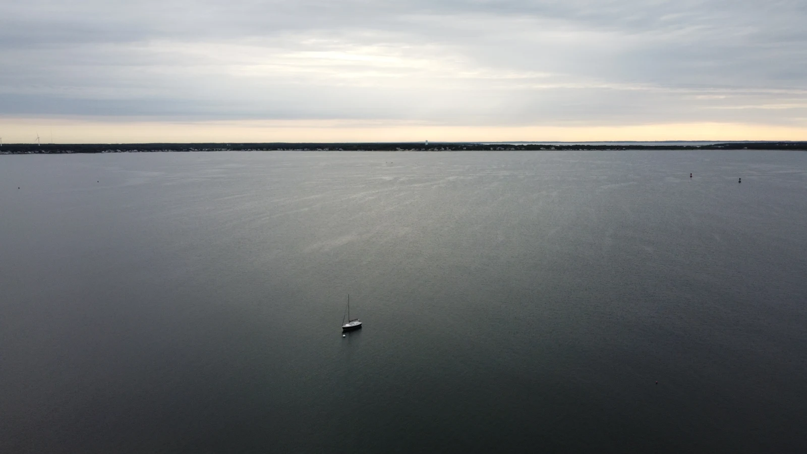 Vue aérienne de la baie devant Sconticut Neck, à Fairhaven, avec un voilier au mouillage et la côte à l’horizon.