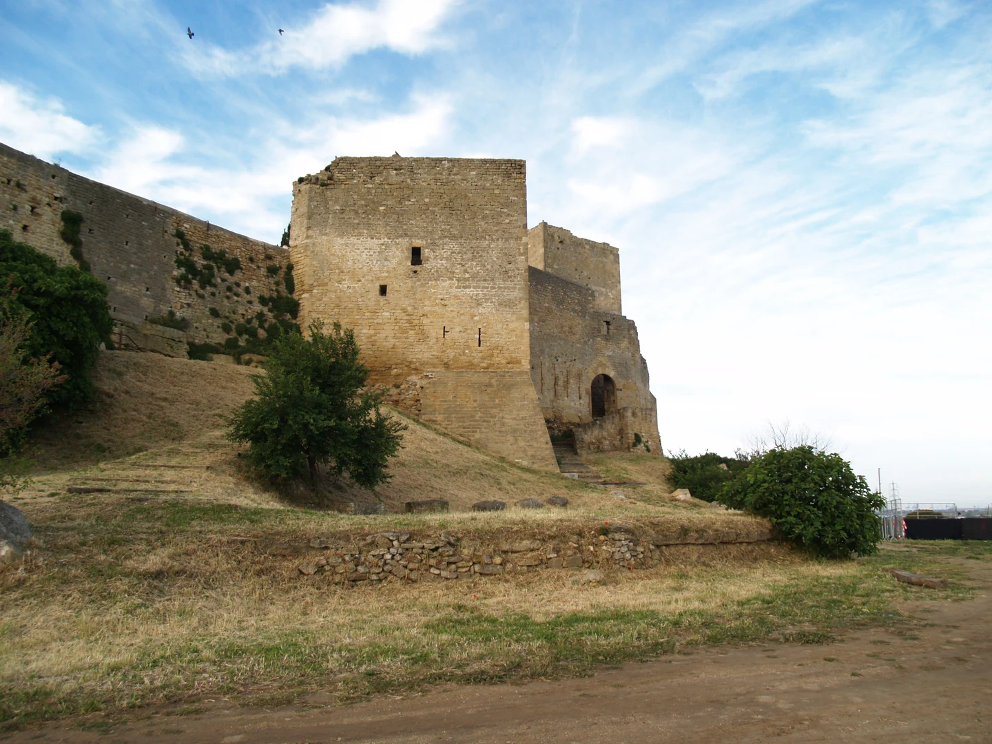 Remparts en pierre de Fos-sur-Mer, sous un ciel bleu et nuageux.