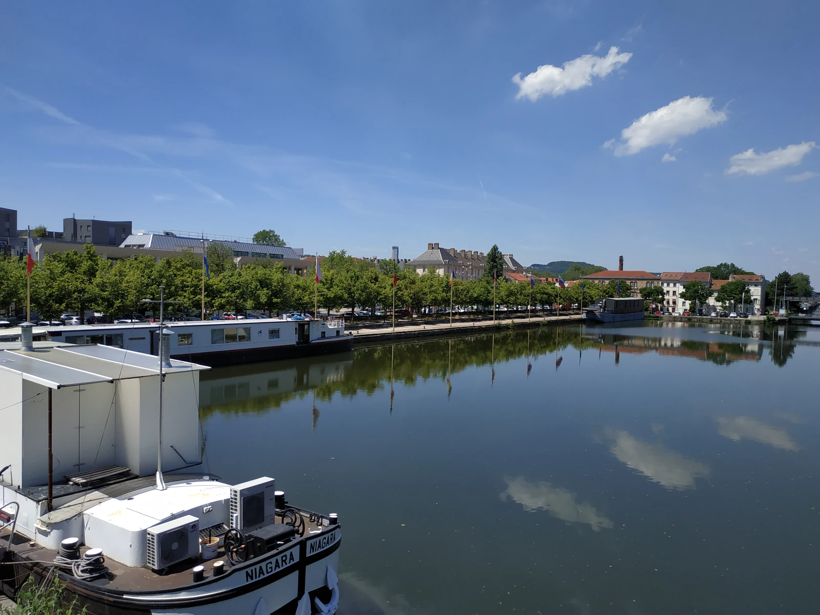 Le bassin et le quai Sainte-Catherine à Nancy, avec des péniches amarrées et des arbres le long de la berge.