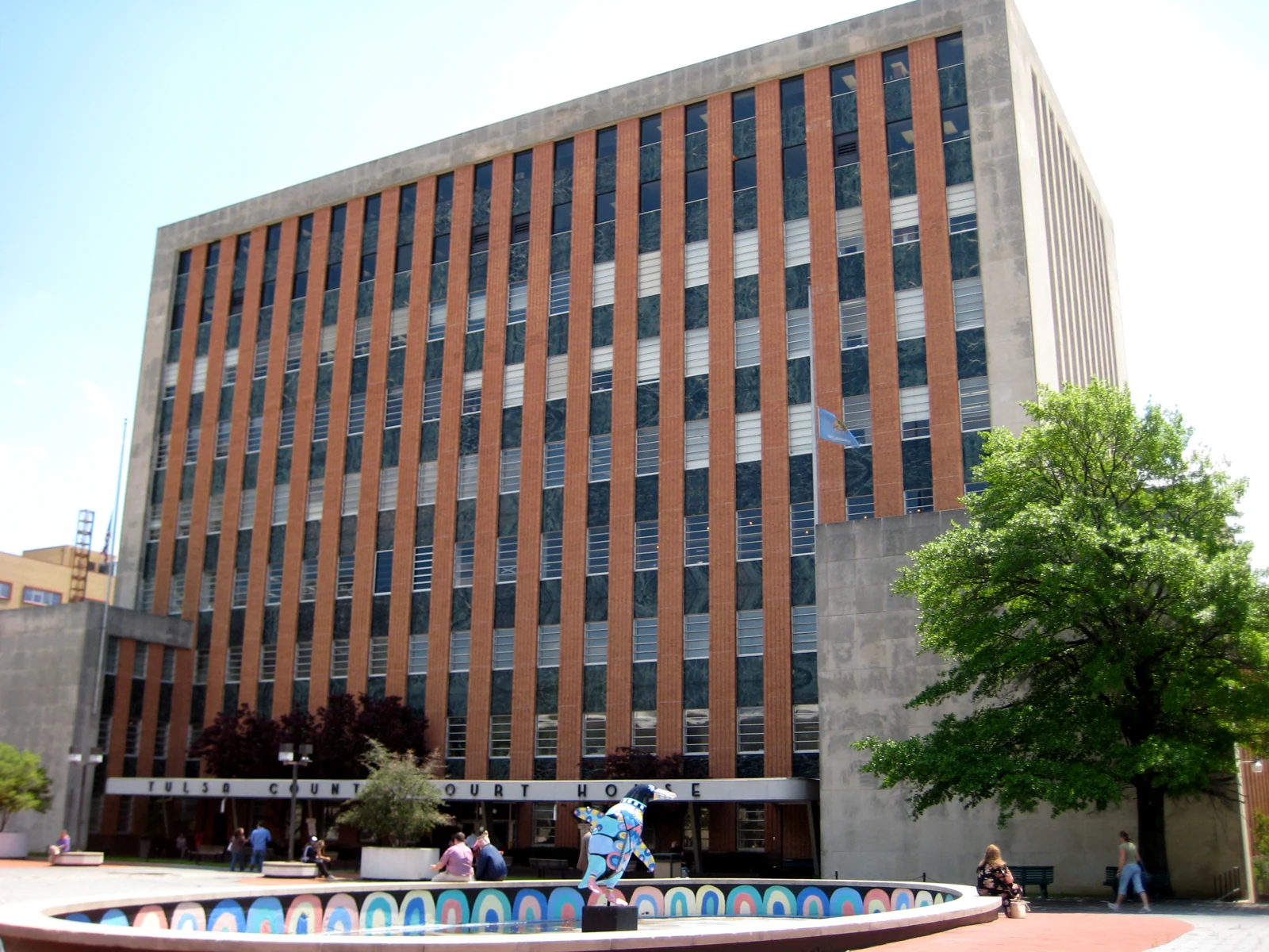 Façade du palais de justice du comté de Tulsa, avec son inscription au-dessus de l’entrée et une fontaine au premier plan.