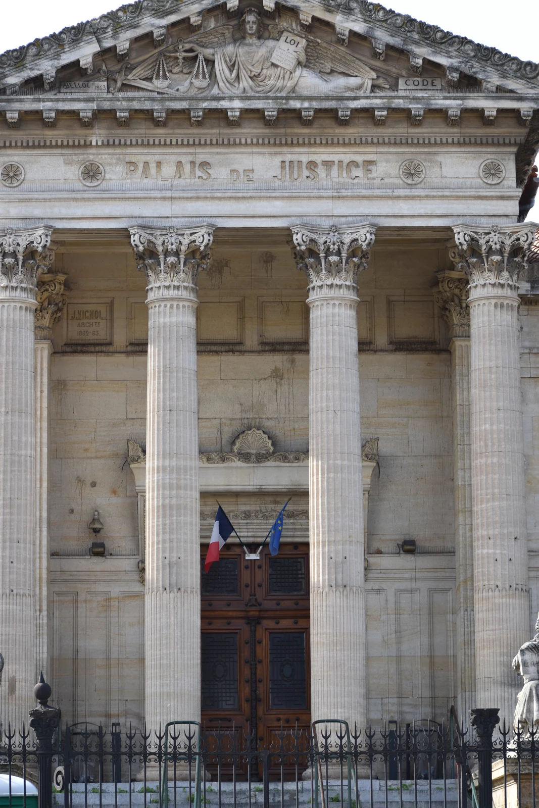Colonnes et fronton du palais de justice de Perpignan, avec les drapeaux français et européen.