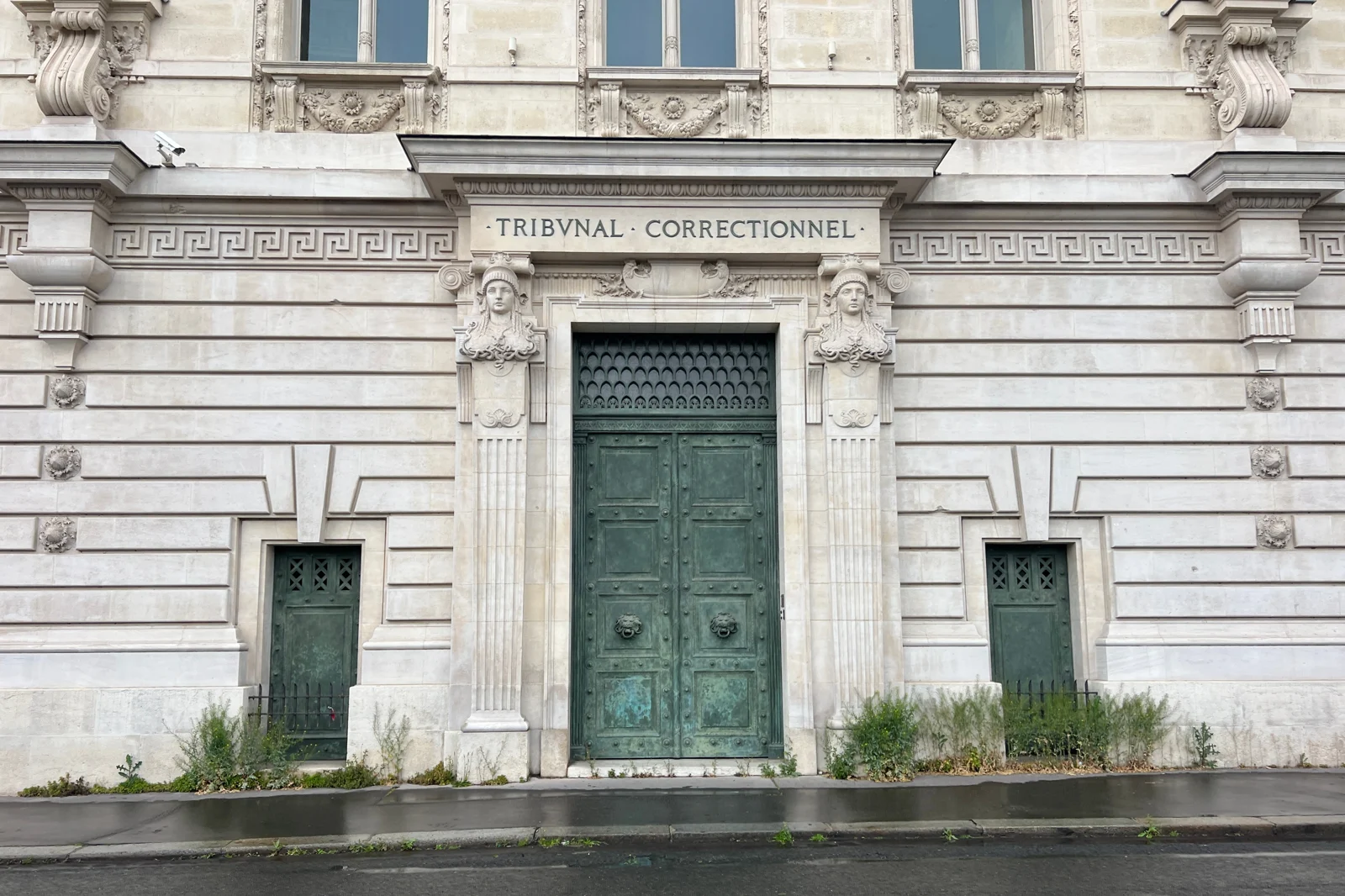 Porte verte et façade en pierre du palais de justice de Paris, avec l’inscription Tribunal correctionnel, en mai 2023.