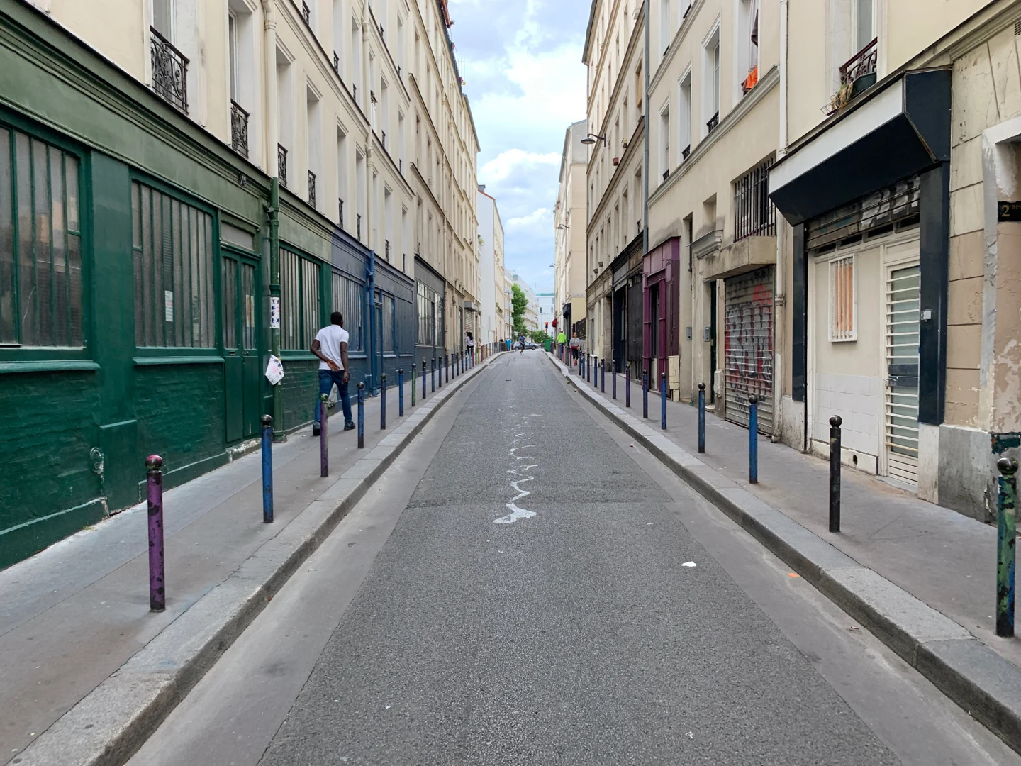 Vue en perspective de la rue Vaucouleurs, entre les façades et les potelets colorés, à Paris.