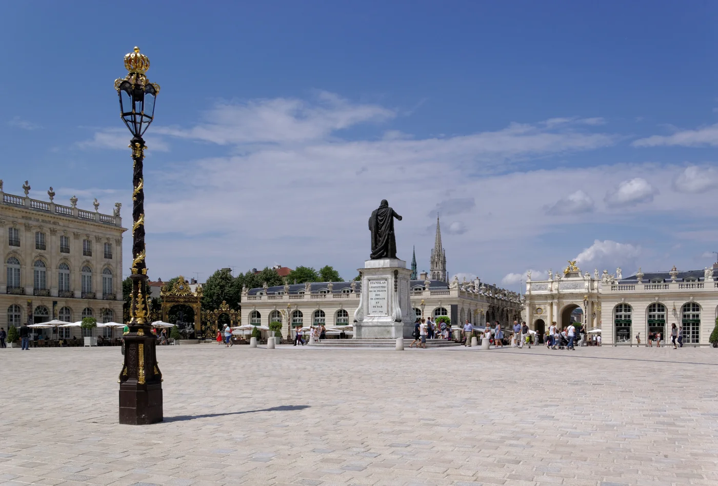 Place Stanislas à Nancy, avec la statue centrale, un lampadaire doré et les façades de la place.