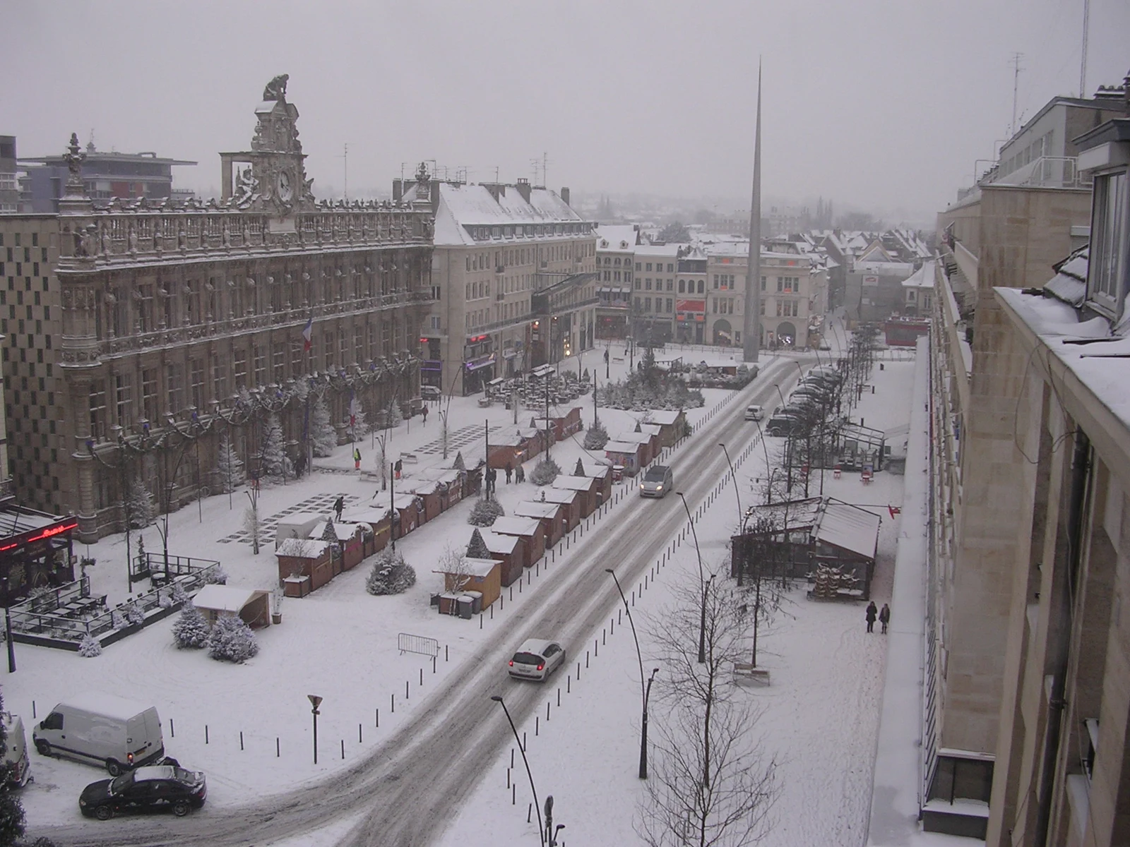 Vue en hauteur de la place d’Armes de Valenciennes sous la neige, avec l’hôtel de ville et les rues voisines.