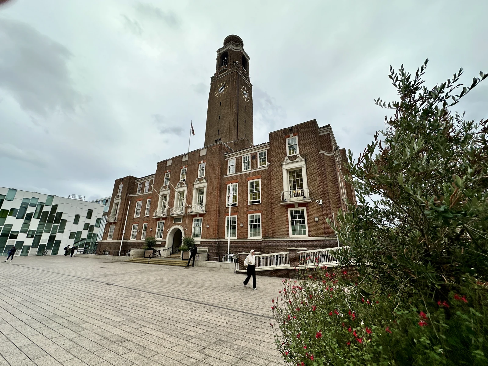La façade de briques et la tour de l’horloge de l’hôtel de ville de Barking devant une place pavée.