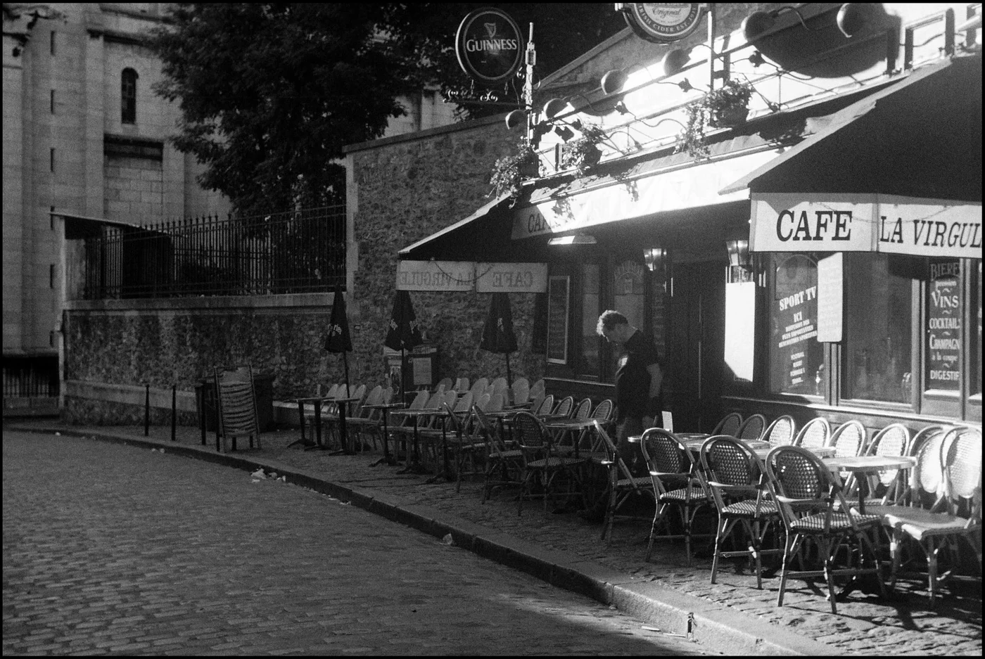 Photographie en noir et blanc d’une terrasse de café à Montmartre.